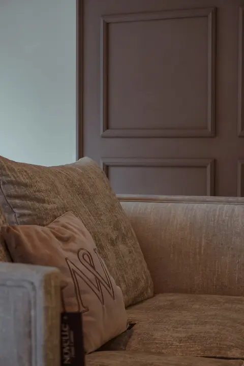 Beżowa sofa na tle drewnianych drzwi – wnętrze z meblami Novelle