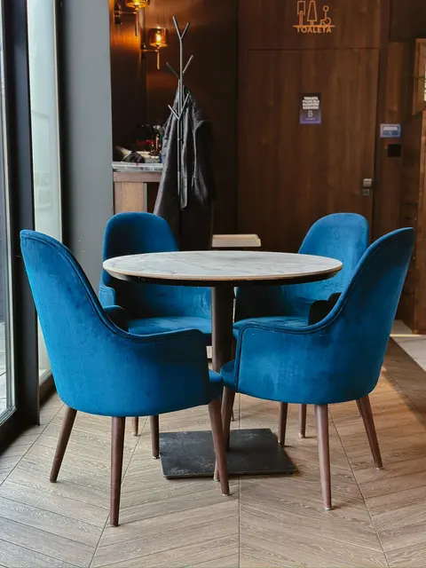 Stolik z marmurowym blatem i granatowe krzesła przy oknie – Cafe Brejk