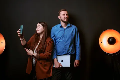 Zespół digital grow w studiu – kobieta z telefonem i mężczyzna z laptopem, strona główna